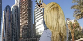 在商业摩天大楼对面用智能手机自拍的快乐女人