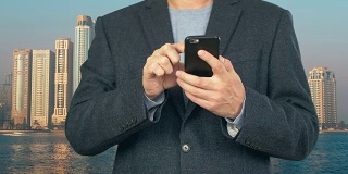 Business man using mobile phone on background modern skyscrapers