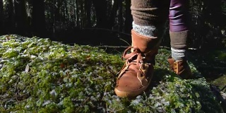 一个活跃的健康的潮女摄影师手拿相机走过森林。一只脚在青苔上踱步的特写。60帧/秒的慢动作。GoPro 6黑色三轴抗菌稳定剂