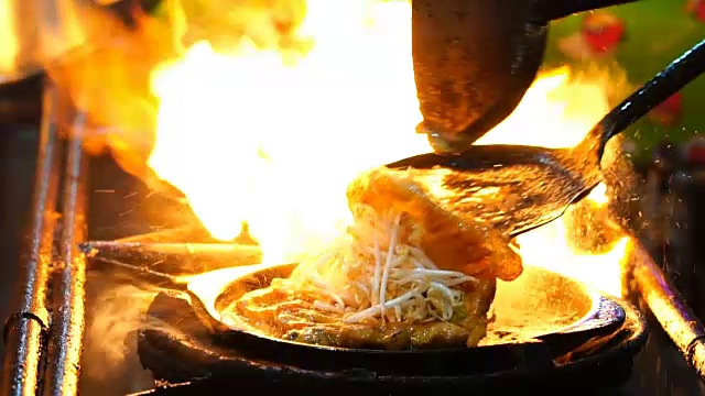 用铁锹在平底锅上翻炒炸虾的特写慢镜头，泰国传统食物，亚洲食物