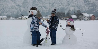 一家人带着孩子，在奥地利小村庄的公园里堆雪人，风景秀丽。