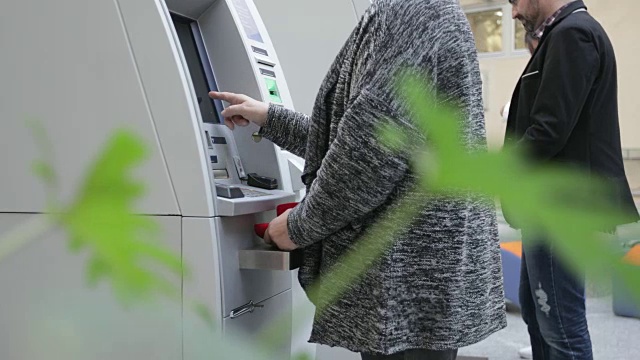 高级女性使用ATM机，手持射击
