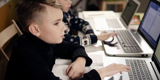 两个小男孩坐在他们的笔记本电脑前学习编程。