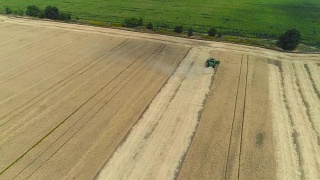 鸟瞰图上的联合收割机和拖拉机在大麦田里工作，麦田里的收割机，绿色收割机在地里工作，从上面看，麦田里收获小麦，空中，全高清视频素材模板下载