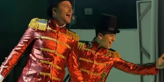 两个穿着燕尾服的英俊男子正在舞台上载歌载舞
