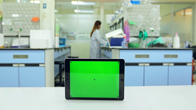 平板绿色屏幕背景与科学家在实验室工作