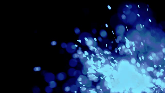 带湍流运动的蓝色电影般的粒子在黑色背景上以浅景深移动在摄像机前