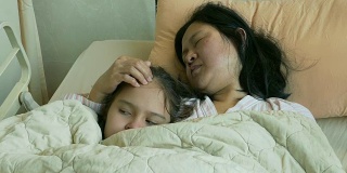 孩子和生病的母亲躺在病床上