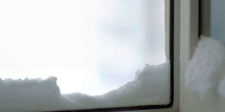 特写抽象的雪飞进房子，躺在打开的窗户上。