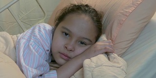 亚裔美国少女躺在病床上，推着娃娃