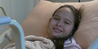 亚裔美国少女躺在病床上微笑着