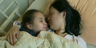 Happy girl kissing mother in hospital bed