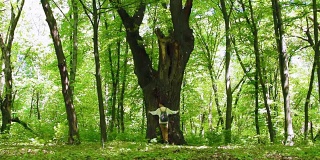 女孩在森林里拥抱大树，热爱大自然。广角镜头