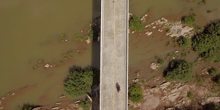航拍冒险摩托车骑在横跨泰国南省南河的一座桥上俯视图