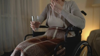 悲伤的老婆婆坐在轮椅上吃药，恢复期，抑郁视频素材模板下载