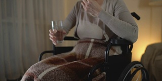 悲伤的老婆婆坐在轮椅上吃药，恢复期，抑郁