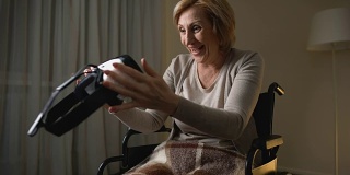 坐在轮椅上的女人，手拿vr眼镜，翘着大拇指，高兴又惊讶
