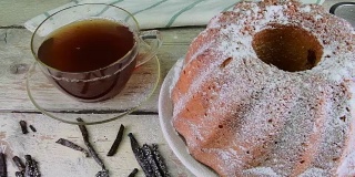 老式的沙蛋糕，一杯红茶和几片香草在木制的背景。蛋黄海绵蛋糕，草莓在乡村白色的背景