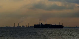 布康岛的燃料、润滑油基础油和特种化学品生产设施的时间流逝，集装箱船在新加坡海峡的夜晚经过