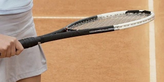 身材苗条的女孩正在用球拍打网球，在场上做赛前热身