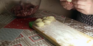 一个女人正在用里面的肉塑造面团来包饺子