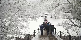 游客们在冬天穿过Shogawa河的吊桥去shirakawa村