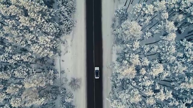 雪地里的汽车行驶在冬日的乡村道路上。鸟瞰图。4 k。