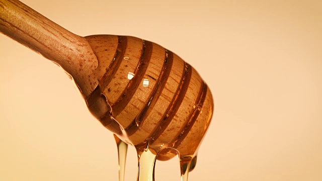 近距离观察滴在蜂蜜勺上的金色甜蜂蜜，4K Dci分辨率