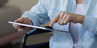 女性在平板电脑上注册手机应用，在线排队到康复中心