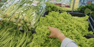 年轻女子在杂货店挑选绿色蔬菜