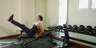 年轻的亚洲健美男子在健身房锻炼腹肌，健康和生活方式的概念