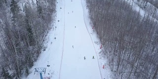 在滑雪场滑雪和滑板滑雪的人们经过滑雪电梯