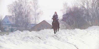 长发女骑手狂野而快速地骑着黑马穿越雪地，慢镜头