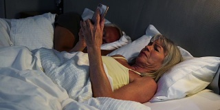 夜不能寐的老年妇女在床上使用手机