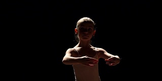 一个年轻的芭蕾舞者在黑色背景上摆姿势