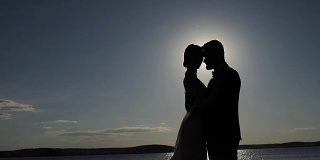 剪影的新娘亲吻拥抱在晨光背光无脸文本copyspace。不认识的男人和女人在相爱的甜蜜时刻在一起。婚礼新娘关系信仰