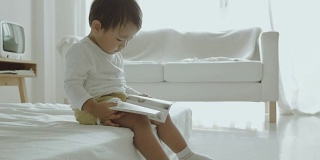 亚洲小男孩在床上看书