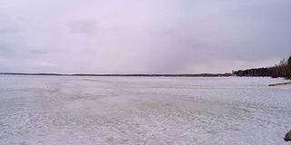 冰冻的湖面和白雪覆盖的森林。冬天在森林湖泊和雪道。冬天的景色，湖面被冰雪覆盖。冬天结冰的湖，灰色的天空和树木或木材