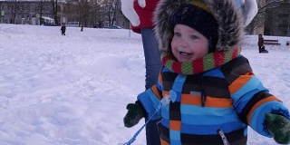 一岁的小男孩穿着暖和的雪衣在冬季公园散步和玩耍。快乐的孩子在冬天的第一场雪中玩耍