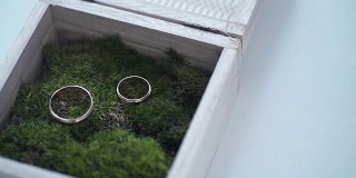 结婚戒指放在一个装满青苔的木盒子里。的婚礼。结婚戒指。一枚镶着宝石的复古订婚戒指被放在一个长满苔藓的木盒子里。盒子放在木桌上