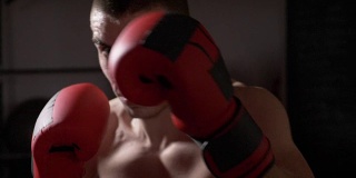 POV近距离的一个运动的肌肉自由搏击运动员看着镜头，而他的影子盒子在慢动作