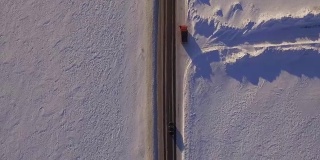 雪地和道路鸟瞰图。越野车在雪地上行驶。鸟瞰图的汽车行驶在道路和田野在冬天
