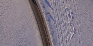 雪地和道路鸟瞰图。越野车在雪地上行驶。鸟瞰图的汽车行驶在道路和田野在冬天