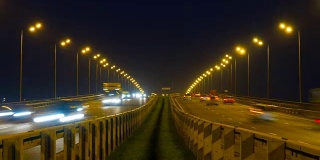 公路交通车辆在夜间时间流逝。汽车行驶在道路上的桥晚上延时。4 k UHD
