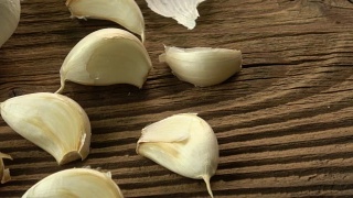 大蒜鳞茎。新鲜的大蒜放在木桌上。视频素材模板下载
