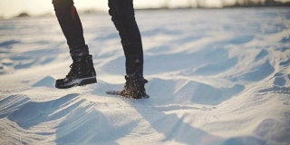 近距离的女人的脚走在雪沙漠在日落。Stabiblized慢动作镜头