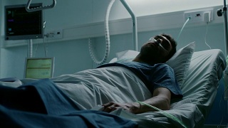 在医院里，一名绝症患者躺在床上忍受痛苦。年轻男子在姑息治疗病房。视频素材模板下载