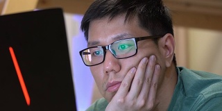亚洲男人在社交媒体上使用笔记本电脑时感到无聊
