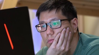 亚洲男人在社交媒体上使用笔记本电脑时感到无聊视频素材模板下载