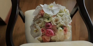 漂亮的婚礼花束白色和粉红色的玫瑰躺在古董椅子上。
